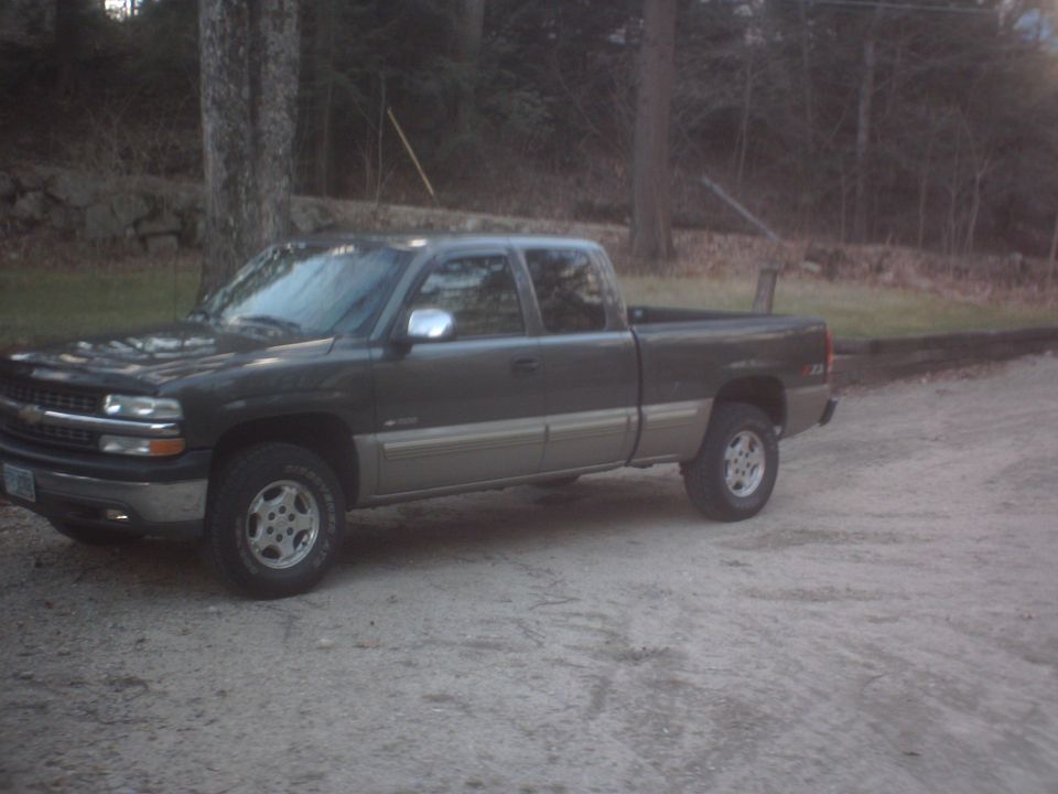Dark green and tan 2002 Chevrolet C/K Pickup truck, side view, parked on a gravel road
