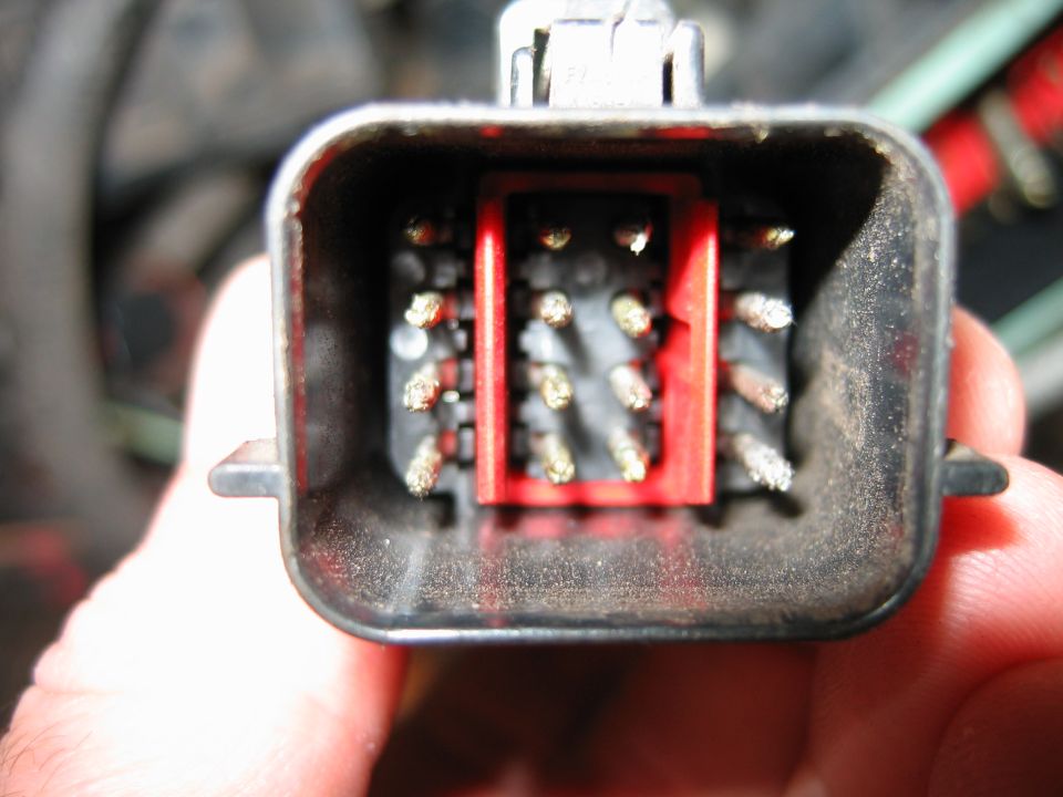 Wiring harness connector with pins and red insert. Supermotors.net logo visible