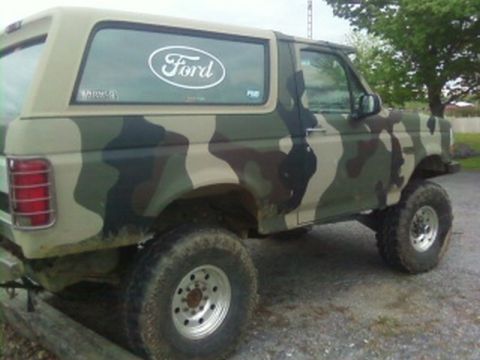 1995 Ford Bronco - Camouflaged 1995 Ford Bronco parked outdoors.