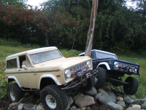 1988 Ford Bronco - Two remote-controlled Ford Bronco-style rock crawlers are positioned on a rocky terrain.