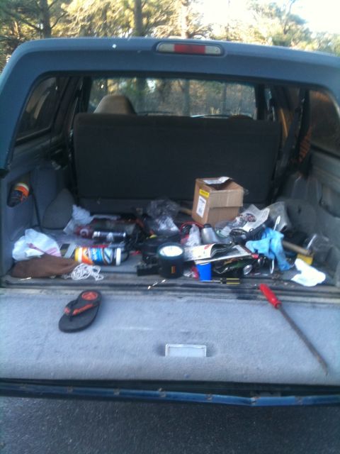 1994 Ford Bronco - The cargo area of an SUV is cluttered with various items, including tools and boxes.