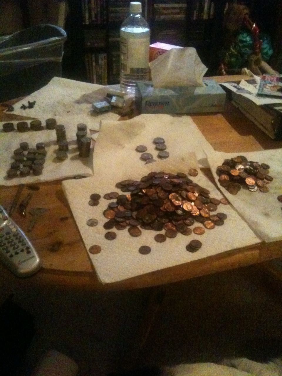 Pile of pennies and other coins spread on paper towels on a wooden table