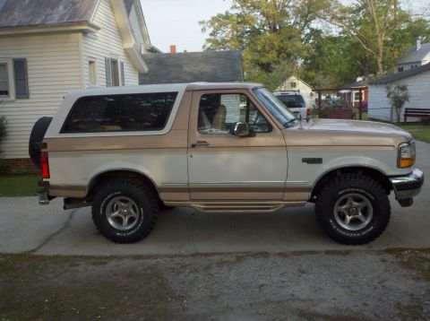 1996 Ford Bronco - This Ford Bronco is parked in front of a house with trees in the background.