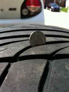 1993 Ford Probe - A coin is stuck in the tread of a tire, with another vehicle blurred in the background.