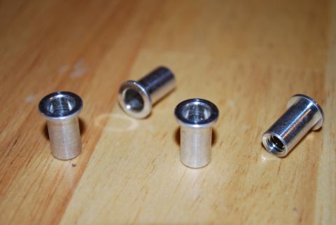 1991 Ford Festiva - Four silver rivet nuts are shown on a wooden surface, likely for installation.