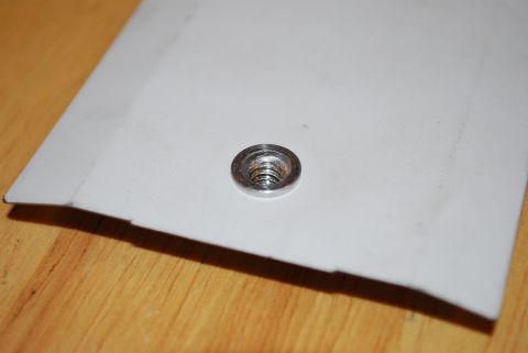 1991 Ford Festiva - Close-up of a metal rivet nut secured in a piece of white plastic.