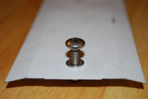 1991 Ford Festiva - A single screw with a spring and washer is shown against a white surface.