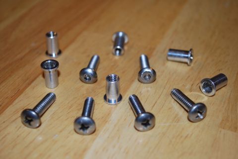 1991 Ford Festiva - A group of metal rivets and screws are scattered across a wooden table, likely for a repair or installation project.