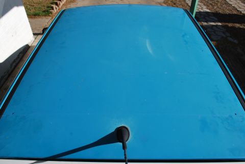 1991 Ford Festiva - The top of a blue car is shown from a high angle, with a black antenna base visible.
