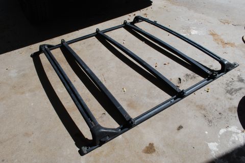 1991 Ford Festiva - A disassembled roof rack is shown on a concrete surface, casting long shadows.
