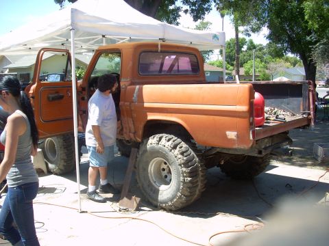 1992 Ford Ranger - An orange pickup truck is parked under a canopy, with people standing nearby.