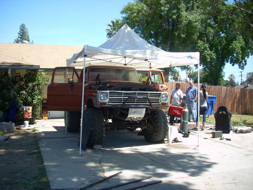 Lifted 1970 Ford F-Series truck with hood open, parked under a canopy. License plate reads LNPE213
