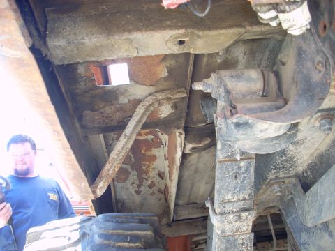1992 Ford Ranger - Undercarriage view of a vehicle, with a man observing the rusty frame and suspension parts.