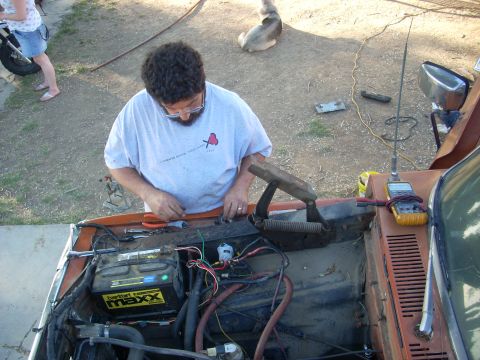 1992 Ford Ranger - A man works on the engine of an orange vehicle, with a dog in the background.