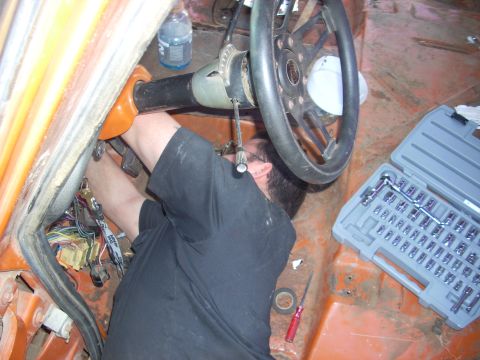 1992 Ford Ranger - A person works on the steering column and wiring inside a vehicle, with a socket set and tools laid out.