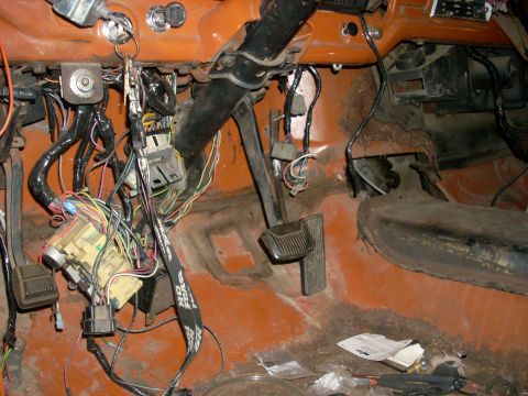 1992 Ford Ranger - The interior of a vehicle shows exposed wiring and pedals, with orange paint visible on the dashboard and floor.