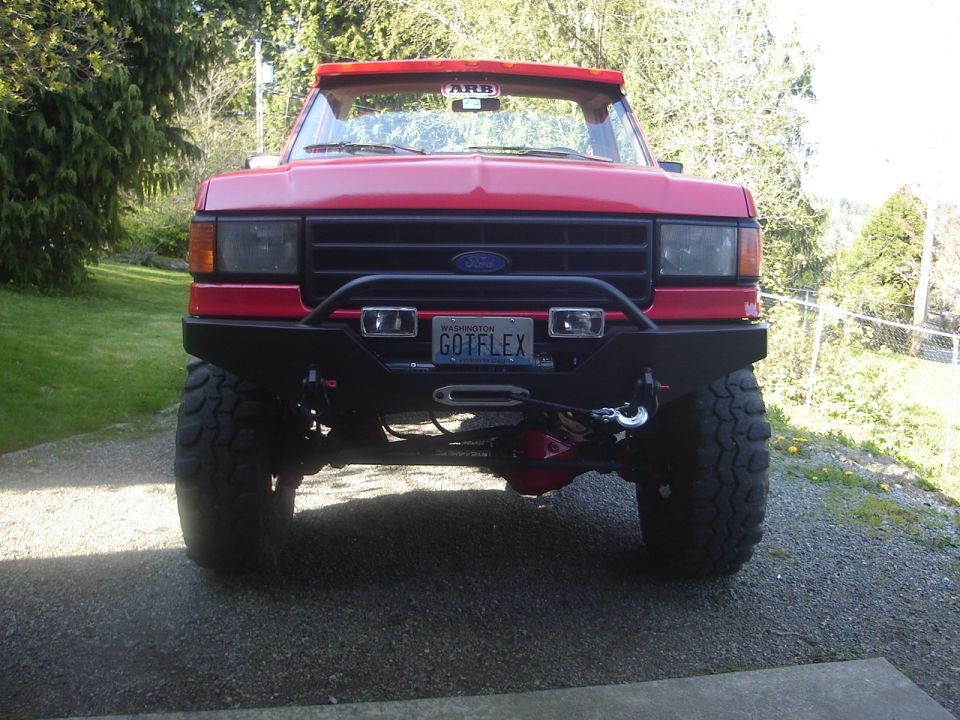 Red 1989 Ford Bronco front view with ARB visor and custom bumper