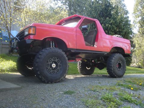 1989 Ford Bronco - Modified 1989 Ford Bronco with extreme lift and off-road tires sits in a driveway.