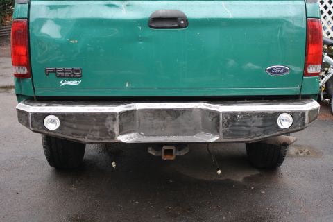 2003 Ford F-250 - The rear of a green Ford F-250 Super Duty pickup truck a custom aftermarket bumper with integrated lights and a tow hitch.