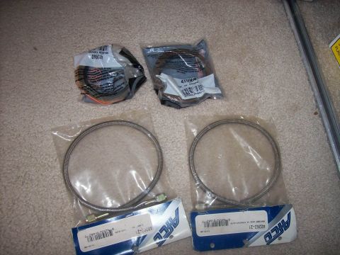 1982 Ford F-100 - Several automotive parts are laid out on a carpeted surface, including two braided brake lines.