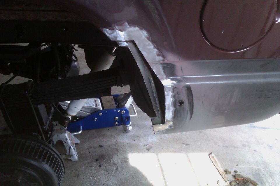 Undercarriage of a vehicle being worked on, showing suspension and body repair