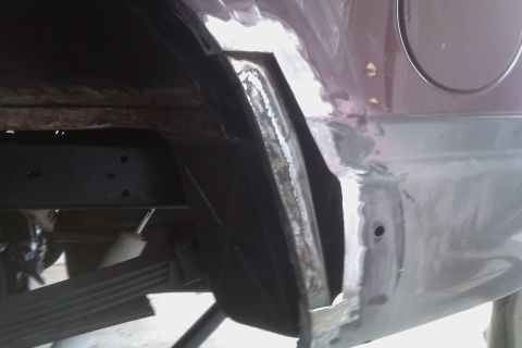 1994 Chevrolet Blazer - Close-up view of a vehicle's rear wheel well during rust repair, highlighting the extent of the damage and the ongoing metalwork.