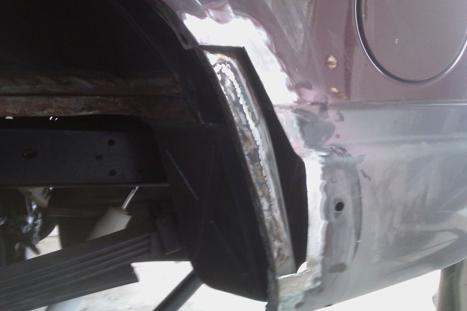 Rear wheel well undergoing repair, showing rust damage and metalwork