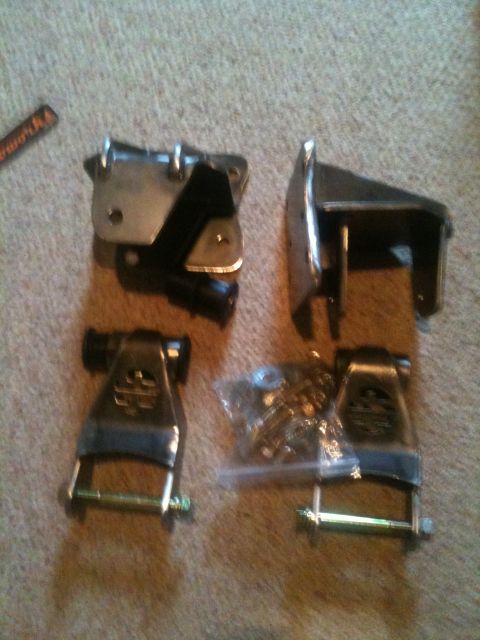 1993 Ford Bronco - Various metal and rubber components of a vehicle lift kit are displayed on a carpeted surface.