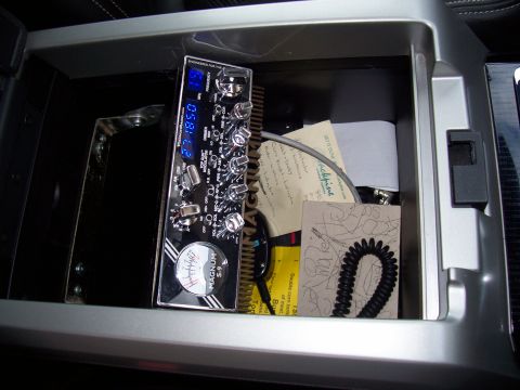 1978 Ford F-150 - A Magnum S-9 CB radio is visible inside the center console of a vehicle, alongside some papers and a coiled cord.
