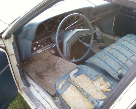 1976 Ford Torino - The interior of a car shows significant wear on the seats and dashboard.