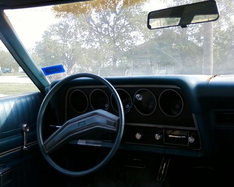 1976 Ford Torino - The interior of a 1976 Ford Torino shows its dashboard, steering wheel, and rearview mirror.
