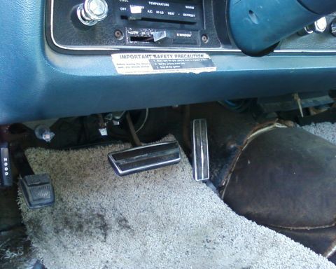 1976 Ford Torino - Interior view of a car's dashboard and pedals, with a safety sticker visible.
