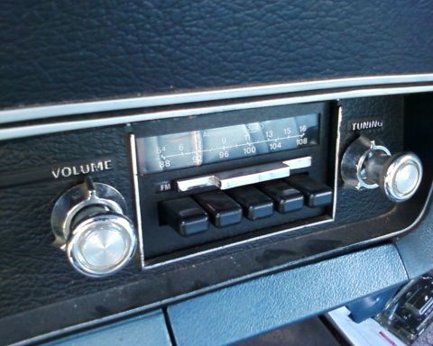 1976 Ford Torino - Close-up of an old car's dashboard radio, showing volume and tuning controls.