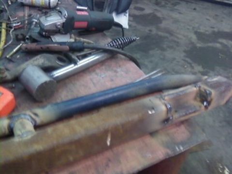 1995 Ford Bronco - Custom fabricated steel rock sliders are shown on a workbench with various tools and equipment.