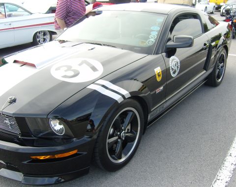 2007 Ford Mustang - A black 2007 Ford Mustang Shelby GT500 with racing stripes and the number 31 is parked next to another vehicle.