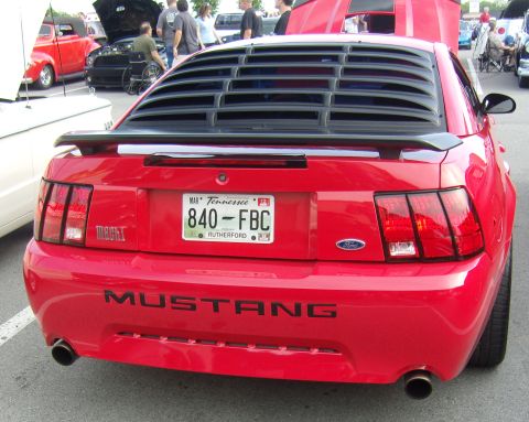 2007 Ford Mustang - Rear view of a red 2007 Ford Mustang with aftermarket louvers and a Mach 1 badge.