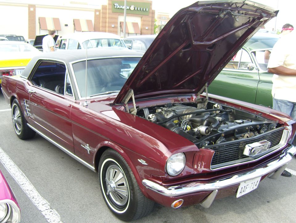 Maroon coupe with black vinyl roof, hood open revealing engine. Chrome grille and bumper. Whitewall tires. License plate visible