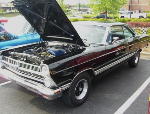 2007 Ford Mustang - A black 1966 Ford Fairlane GT is parked with its hood up, revealing the engine bay.