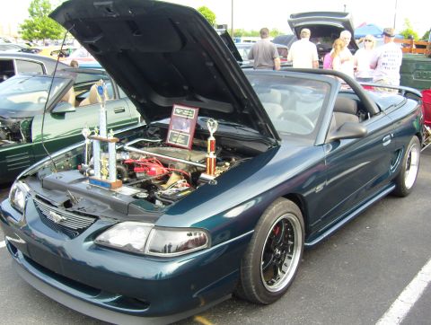 2007 Ford Mustang - A dark green convertible, identified as a 1994 Ford Mustang, is displayed with its hood open, trophies.
