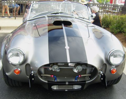 2007 Ford Mustang - A classic silver Shelby Cobra replica with dual black racing stripes is parked outdoors.