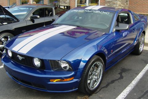 2007 Ford Mustang - A blue Ford Mustang with racing stripes is parked next to another Mustang.