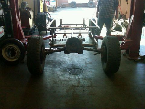 1995 Ford F-150 - The rear of a vehicle frame is visible, supported by a lift in a workshop setting.