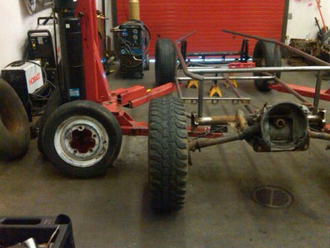 1995 Ford F-150 - A partially assembled vehicle frame is shown in a workshop setting with various tools and equipment in the background.