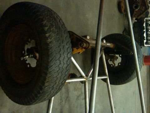 1995 Ford F-150 - The front axle and wheels of a vehicle are supported by a metal frame in a workshop setting.