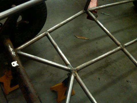 1995 Ford F-150 - This image shows the construction of a custom roll cage, likely for a project vehicle, with a tire and jack stands visible.