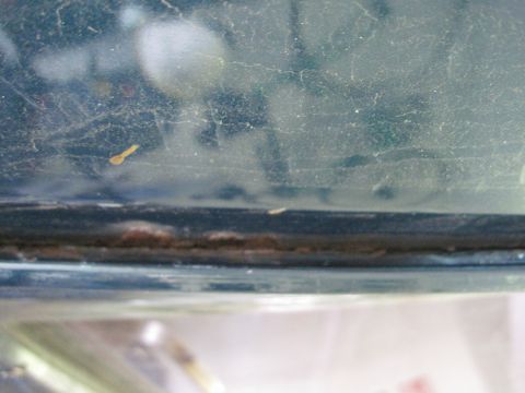 1979 Ford Bronco - The edge of a vehicle's window shows signs of wear and tear, with dust and rust visible.