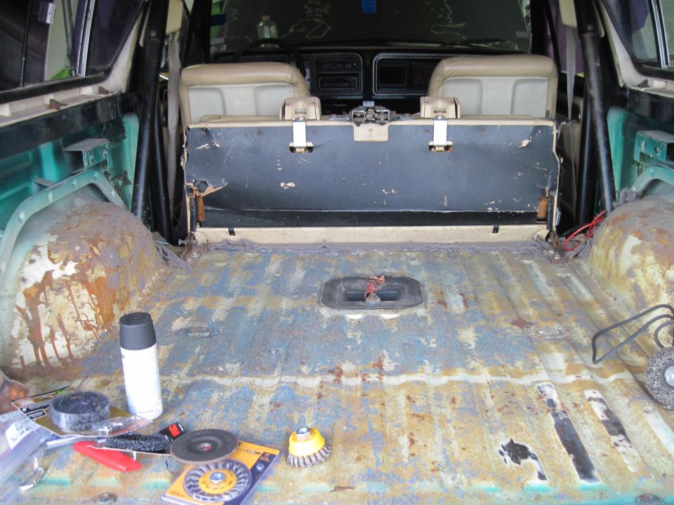 Interior rear cargo area of a 1978 Ford Bronco with worn seats and rusted floor