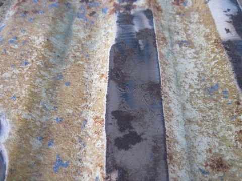 1979 Ford Bronco - Close-up of corroded metal surface with visible texture and paint remnants.