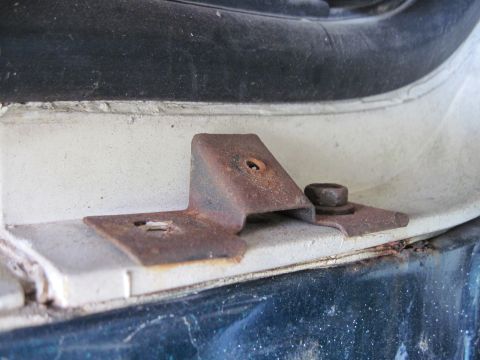 1979 Ford Bronco - A close-up view of a corroded metal bracket and fastener on a vehicle's exterior.