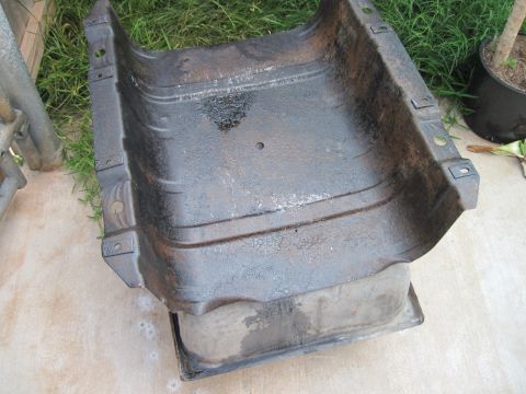 1979 Ford Bronco - A weathered metal component, possibly from a vehicle's undercarriage, sits outdoors.